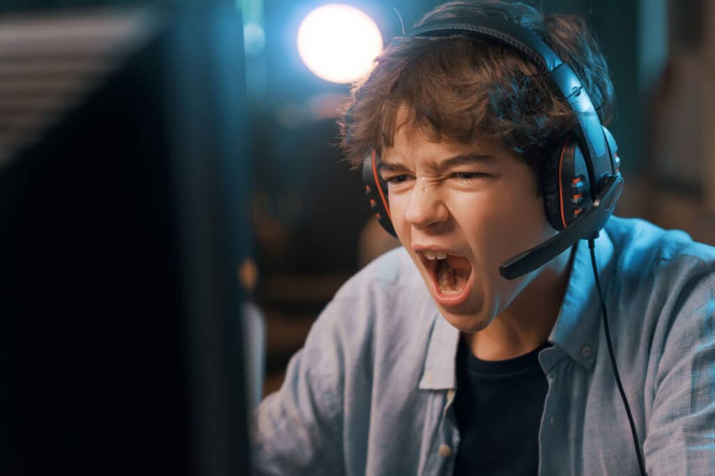 teenage boy wearing headphones and screaming at computer screen while gaming needs to learn 5 tips on managing anger as a teen