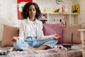 teenage girl seated cross-legged on floor with relaxed and reflective expression learning the importance of meditation for teens